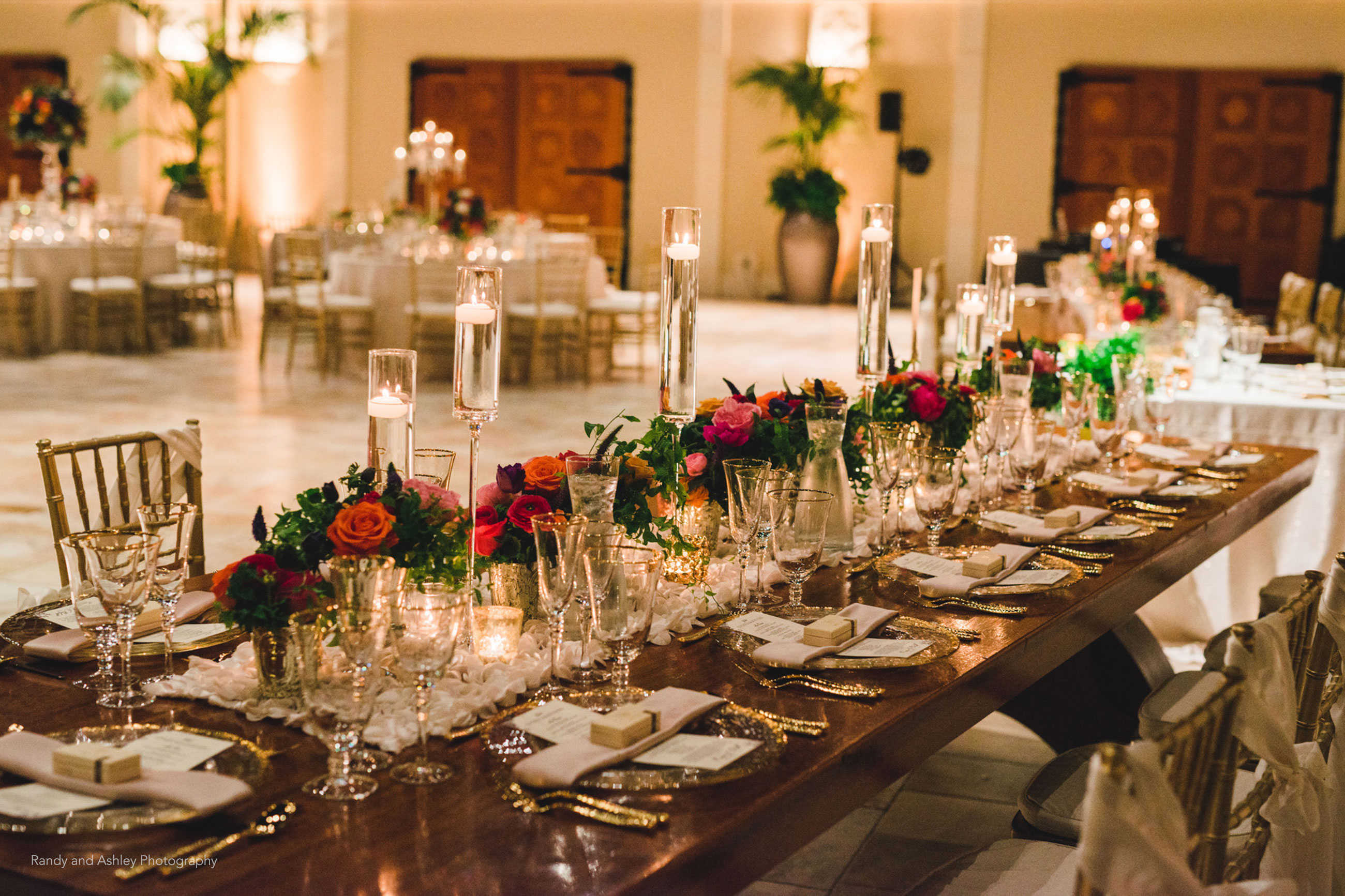 Elegant candlelit wedding reception table with gold and roses at Casa Real at Ruby Hill Winery (www.casarealevents.com).  Photo by: Randy and Ashley Photography; Florals: Enchantment Floral; Linens: Napa Valley Linen; Glassware, Flatware and Chargers: Pleasanton Rentals