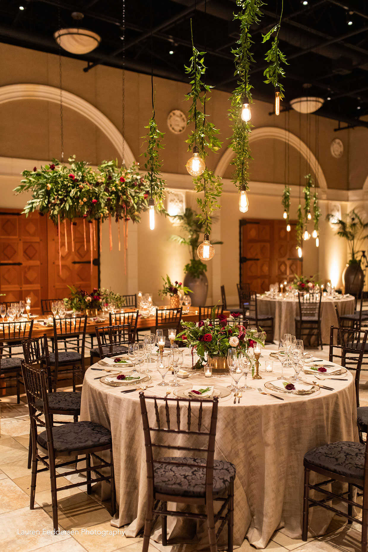 Unique boho wedding reception with hanging greenery and Edison light bulbs at Casa Real at Ruby Hill Winery (www.casarealevents.com).  Photo by: Lauren Feddersen Photography; Florals (and floral chandelier): Nicole Ha Design; Lighting: Fantasy Sound Event Services; Linen: Pleasanton Rentals